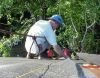 Hanging onto the rope while positioning a piece of roofing. 
